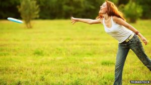 "A woman is throwing a frisbee in a park"