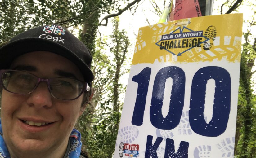 Janet smiling in front of a 100km marker